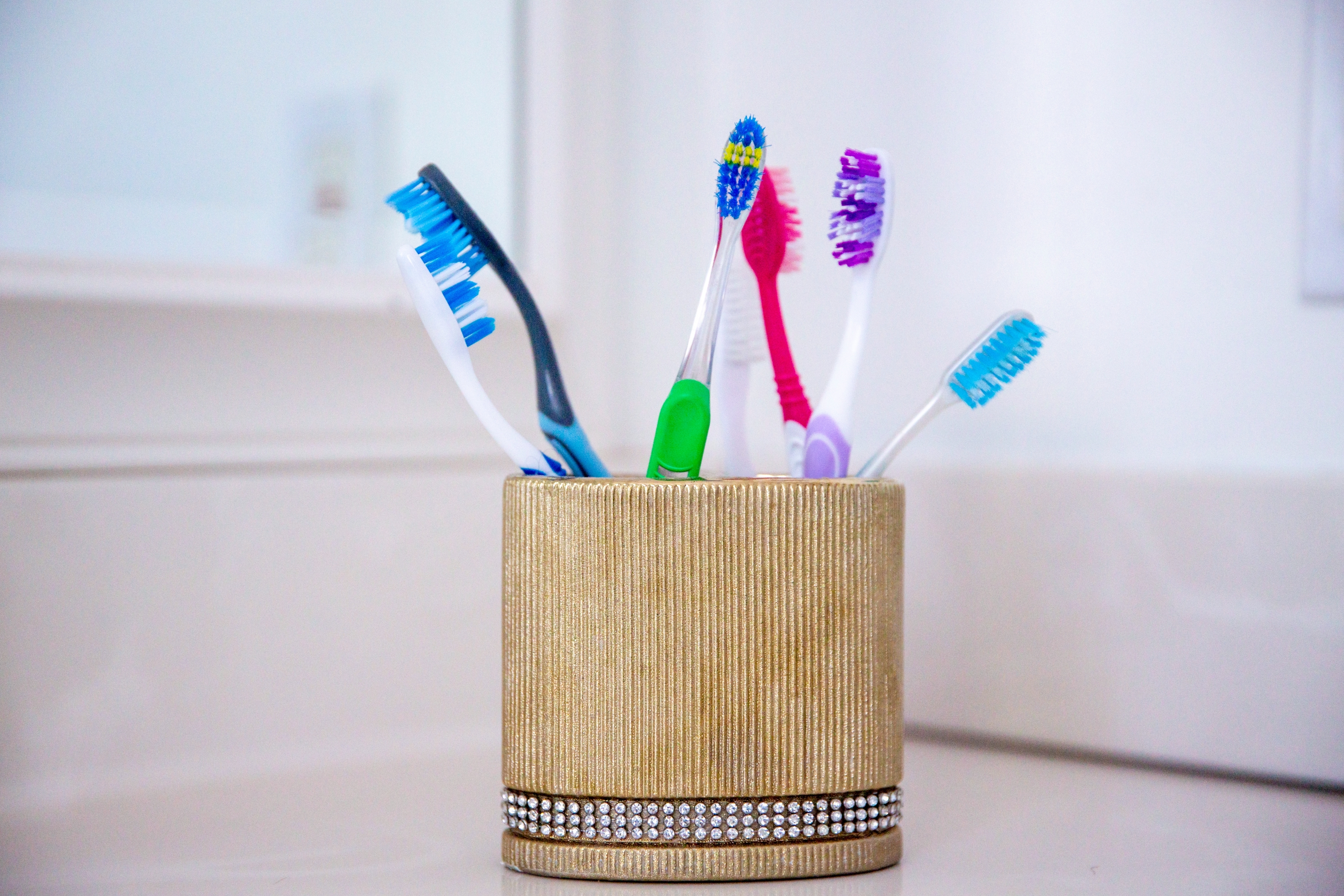 Toothbrush holder with colorful toothbrushes on a bathroom counter