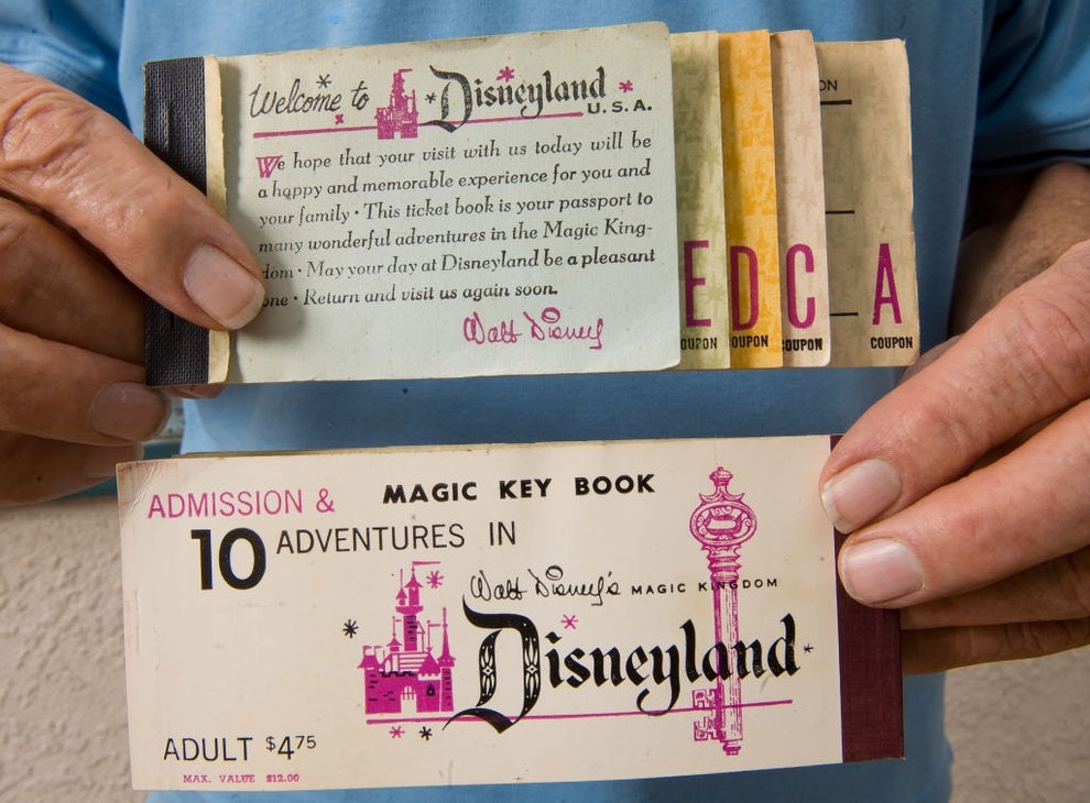 Person holding vintage Disneyland ticket book with admission and adventures coupons, showcasing nostalgic theme park memorabilia