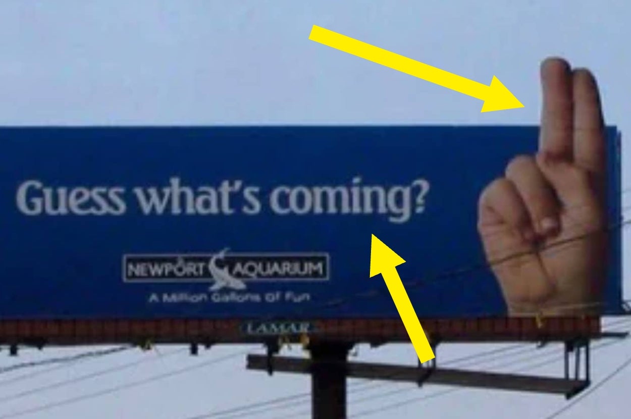 Billboard with "Guess what's coming?" Text and hand showing a split-finger gesture, promoting Newport Aquarium. Yellow arrows point to text and gesture