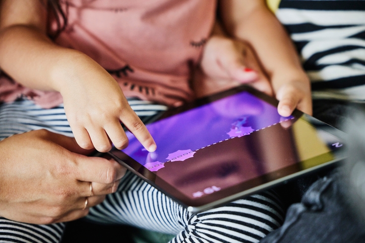 Child using a tablet, playing an interactive game with adult assistance