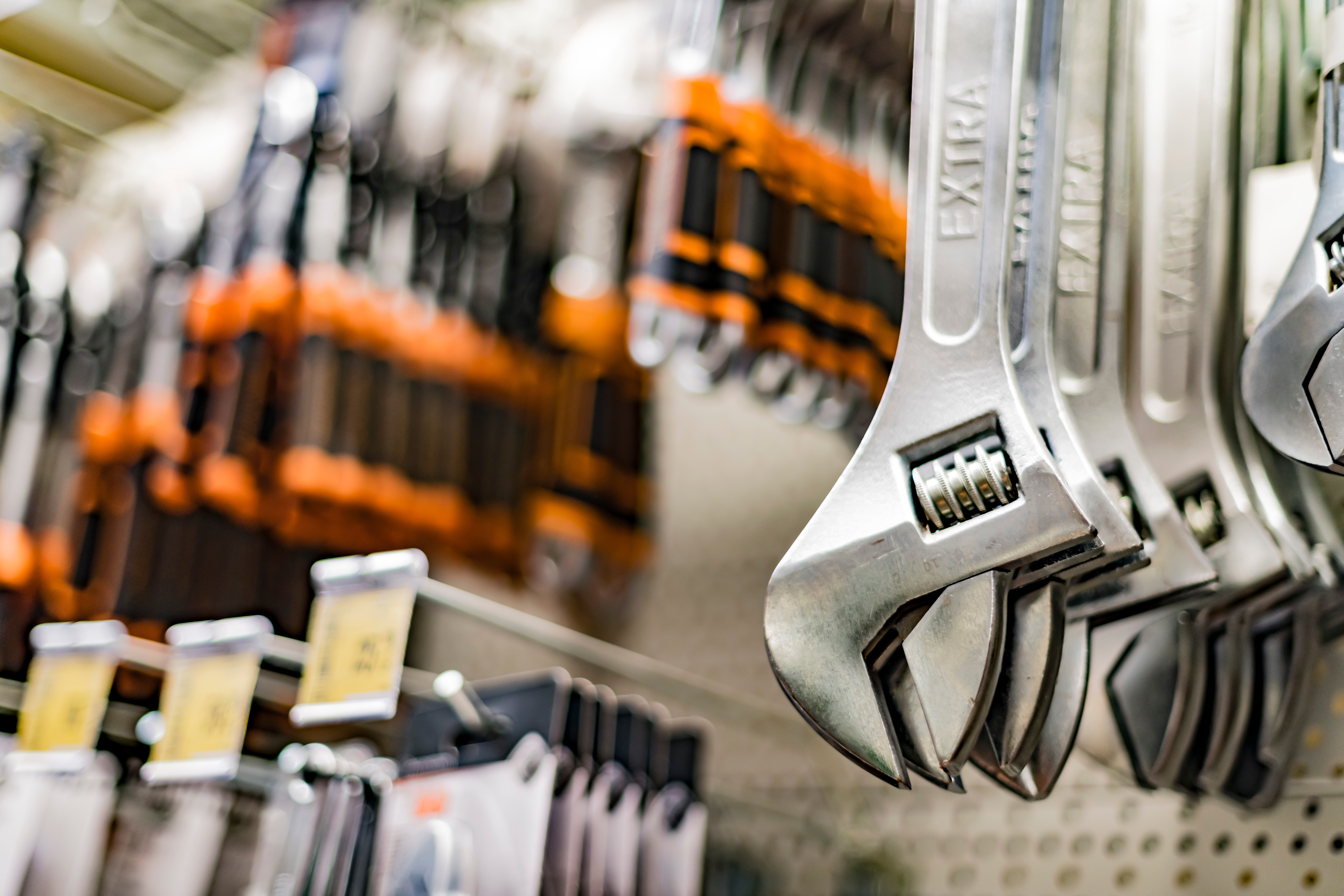 Wrenches hanging on a store display, with other tools blurred in the background, creating a hardware store scene