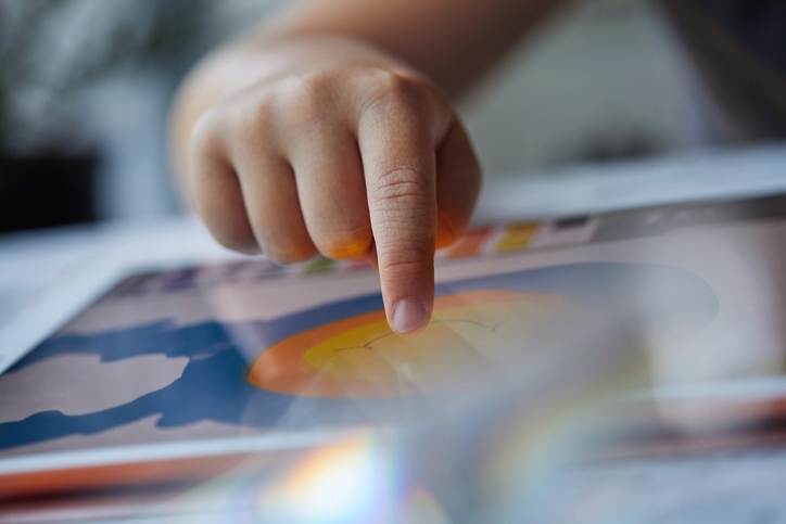 A person points at artwork on a tablet screen, focusing on a circular shape