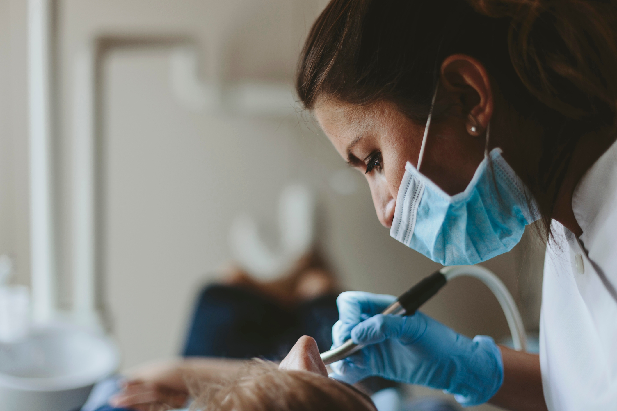 Dentist wearing a mask and gloves performs a dental procedure on a patient in a clinic
