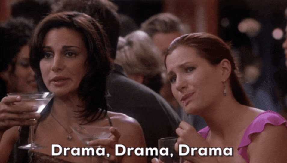 Two women holding drinks at a social event, looking intrigued. Subtitles read: "Drama, Drama, Drama."