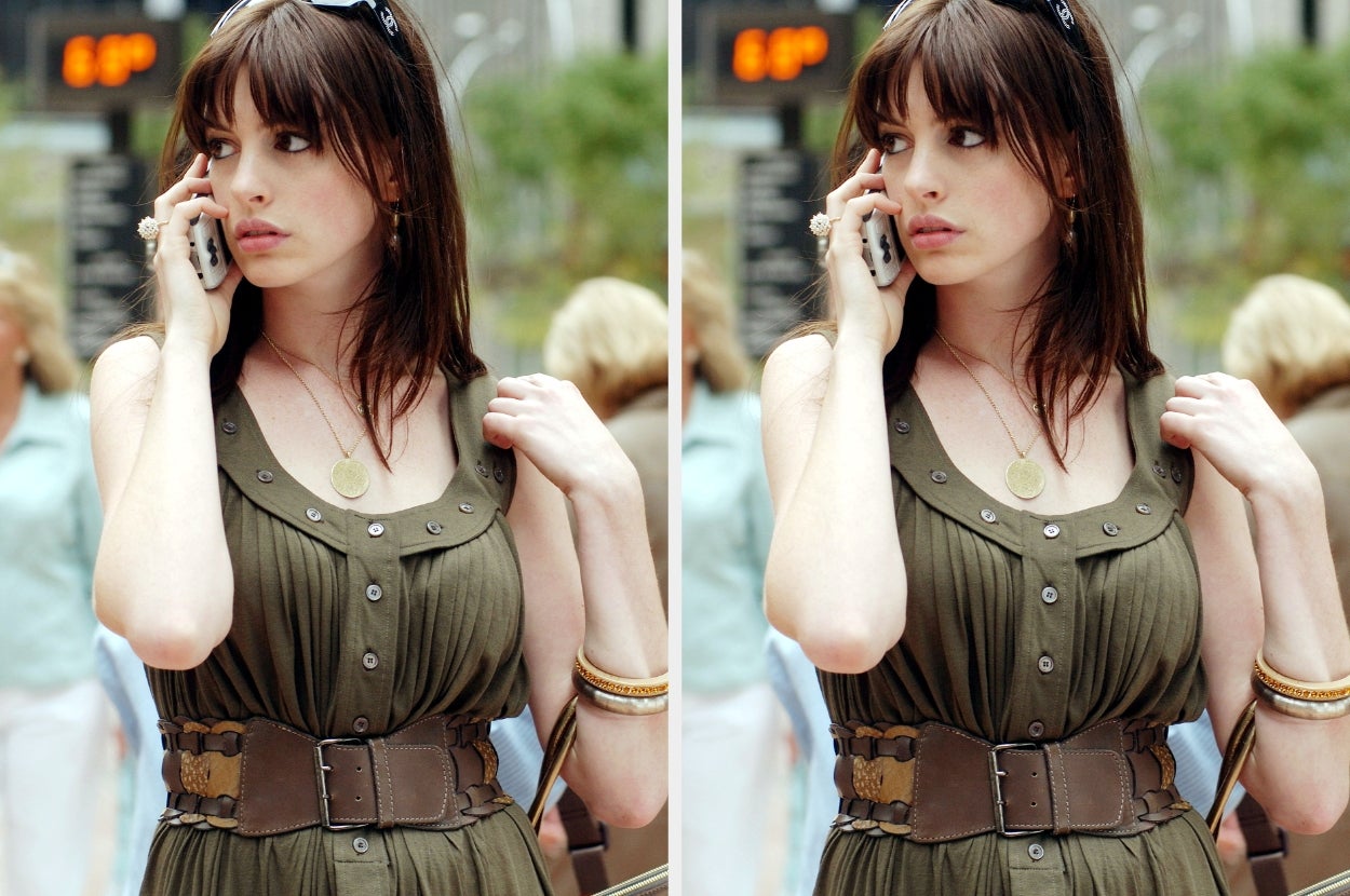 Person outdoors, talking on the phone, wearing a sleeveless dress with a wide belt. Other people are blurred in the background
