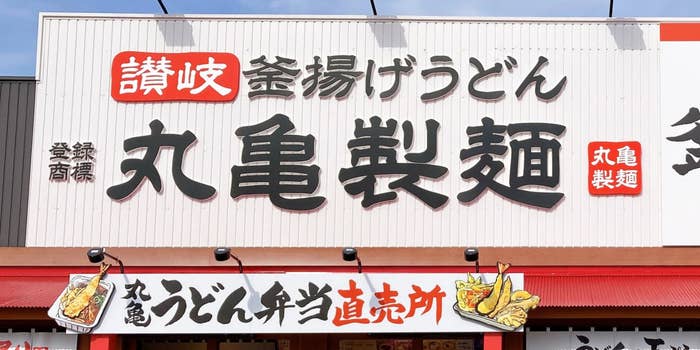讃岐釜揚げうどん専門店「丸亀製麺」の看板と弁当販売エリアの表示。
