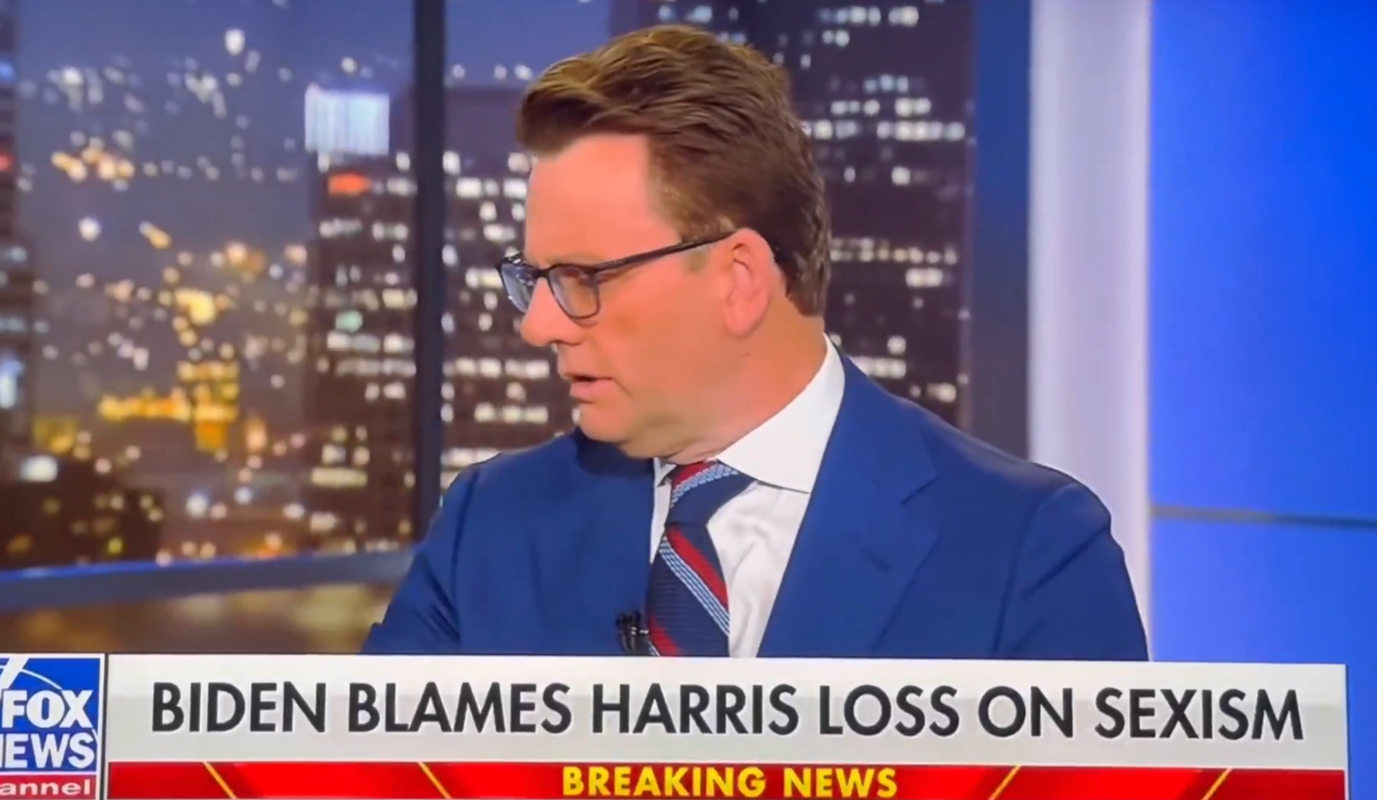 News anchor on TV discussing topic related to "Biden blames Harris loss on sexism," with headline and cityscape backdrop