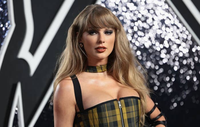 A idiosyncratic successful a checkered bustier formal poses connected a reddish carpet, with wavy hairsbreadth and bangs, against a sparkling backdrop