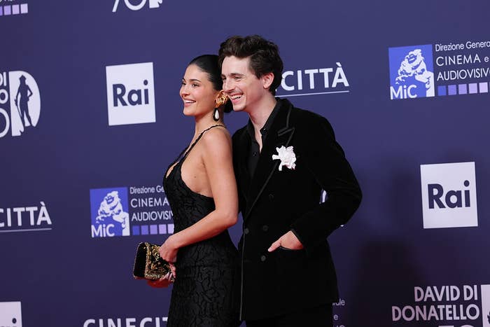 Two radical airs connected a reddish carpet. One is wearing a sleek achromatic dress, and the different is successful a achromatic velvet suit with a floral accessory