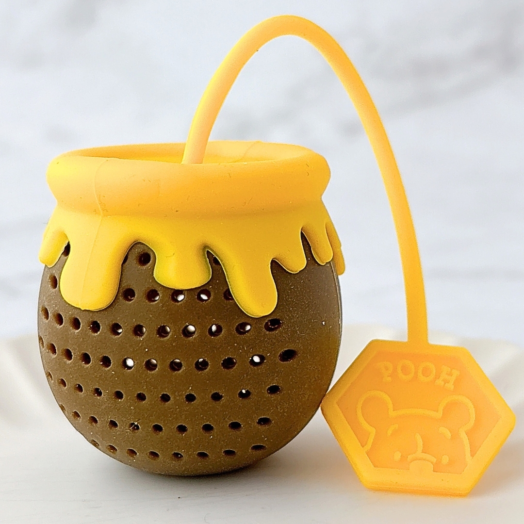 蜂蜜壺型の茶こしが写っています。ラベルには「POOH」とリラックマの顔のデザイン。