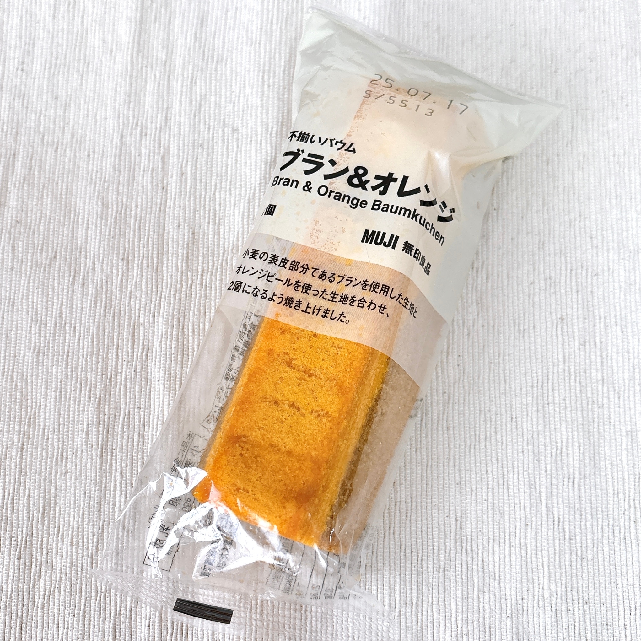 ブランとオレンジ味のバウムクーヘンが透明な包装に入っている。ムジの商品タグが付いている。