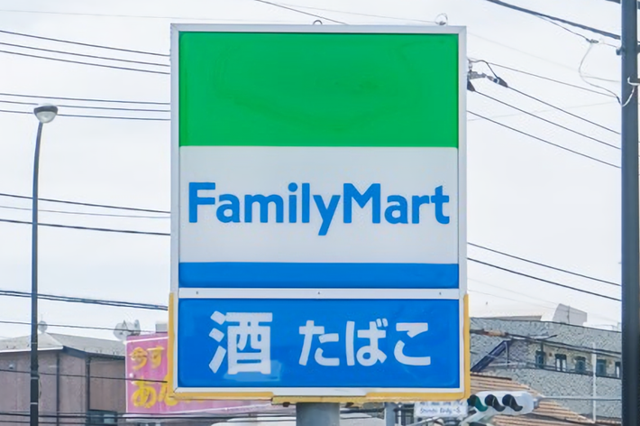 ファミリーマートの看板が街中に立っている。下部に「酒 たばこ」の表示がある。