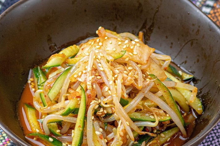 大きなボウルに盛られたスパイシーなもやしとキュウリのサラダ。ゴマがトッピングされています。