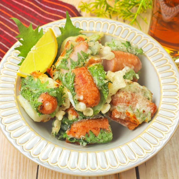 皿に盛られたソーセージの天ぷら。大葉とレモンが添えられている。