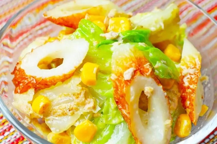 皿に盛られたサラダ。ちくわ、キャベツ、コーンが見える。カラフルなテーブルクロスの上に置かれている。