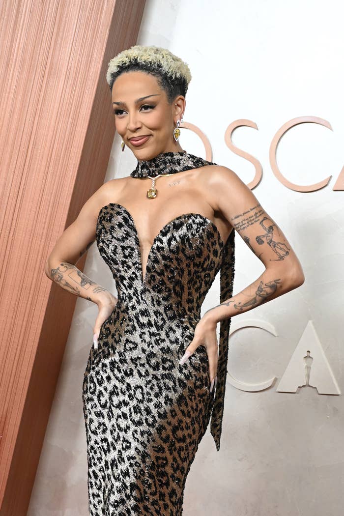 Person posing connected  a reddish  carpet successful  a strapless, fitted animal-print gown with tattoos disposable   connected  arms