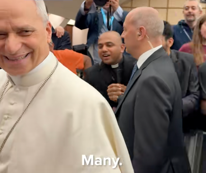 A smiling religious leader with onlookers in the background