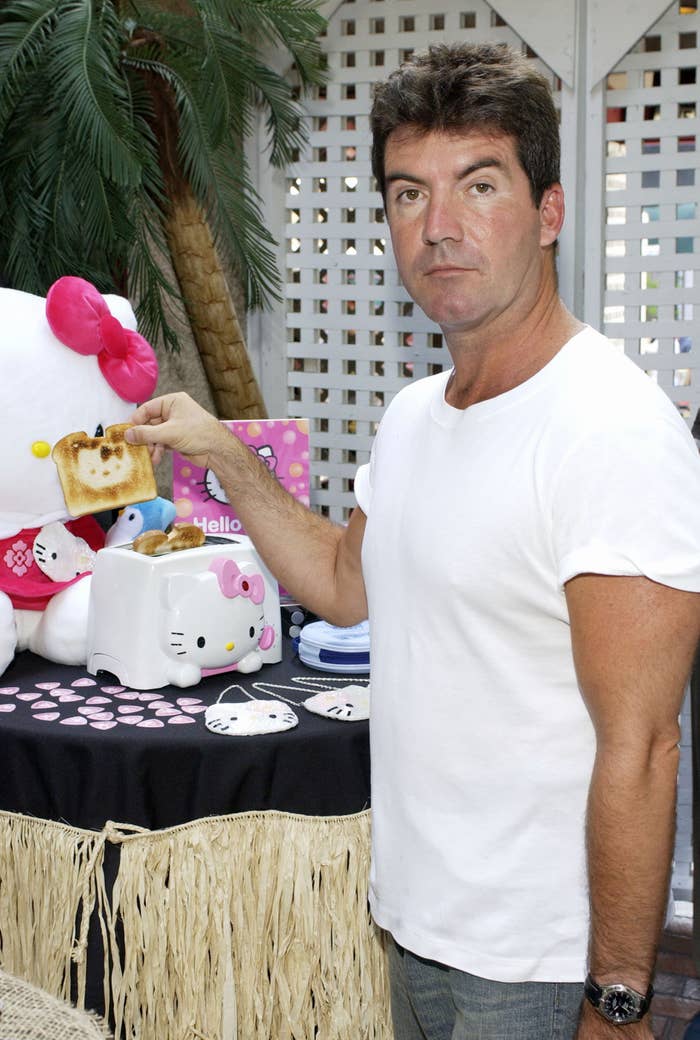 Person in casual attire holding a piece of toast from a Hello Kitty toaster, standing near Hello Kitty merchandise display
