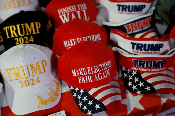 Hats with slogans like &quot;Trump 2024&quot; and &quot;Make Elections Fair Again&quot; are displayed on a table