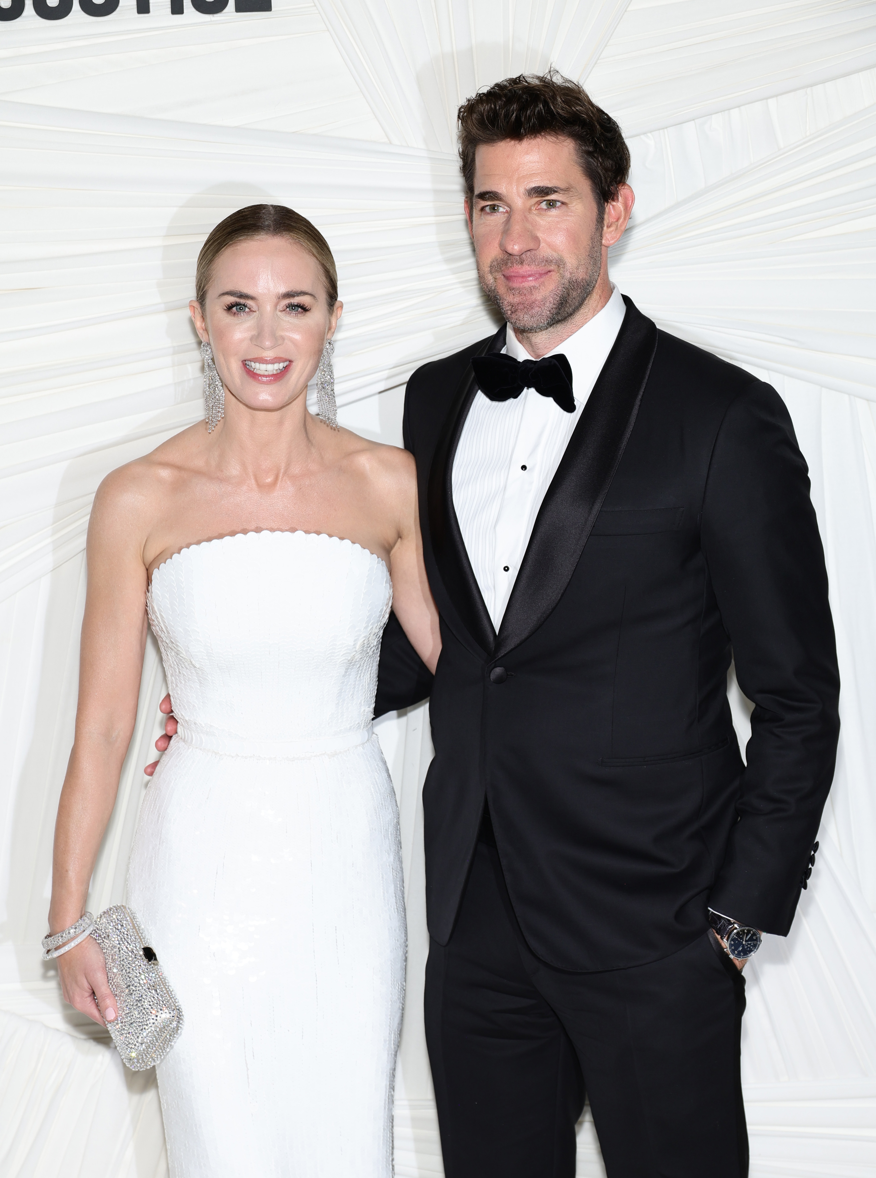 A woman in a strapless gown and a man in a tuxedo pose together at a formal event