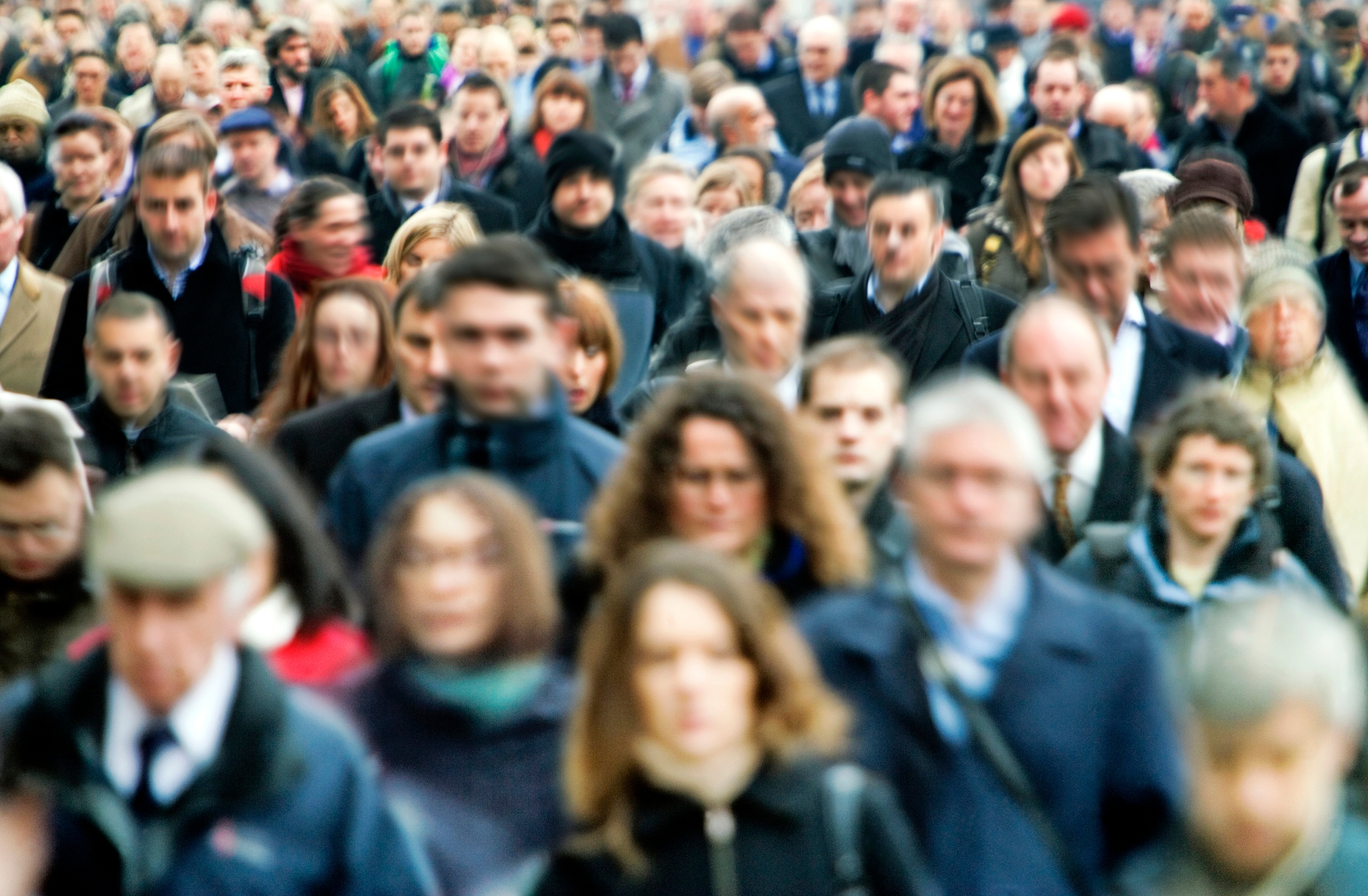 Crowd of people walking on a busy street, appearing focused on their destination