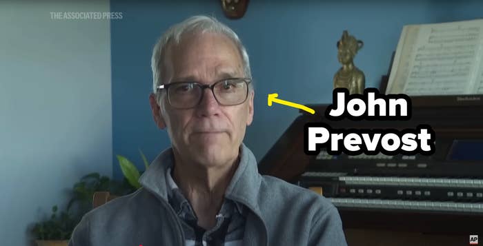 An older person wearing glasses sits in front of a musical organ and sheet music, with a thoughtful expression