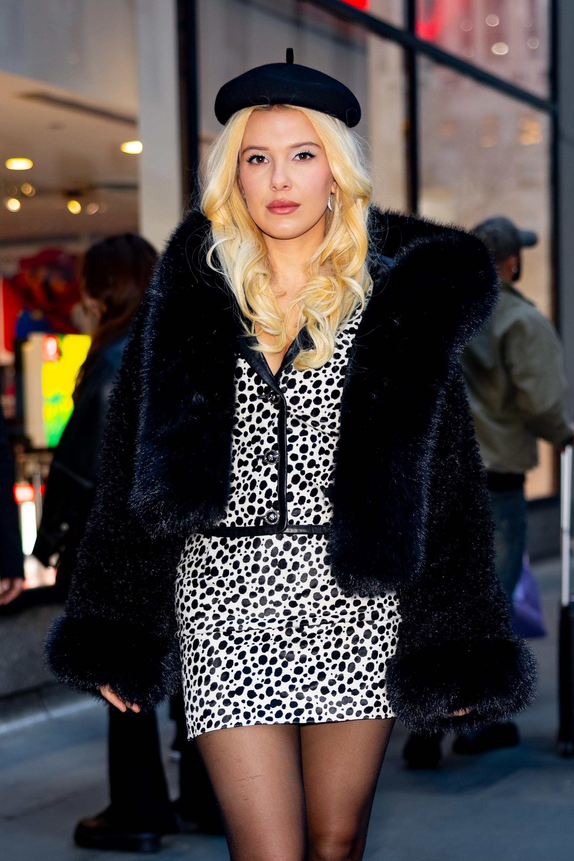 Person wearing a leopard print mini dress, large fur coat, and beret, walking in an urban setting