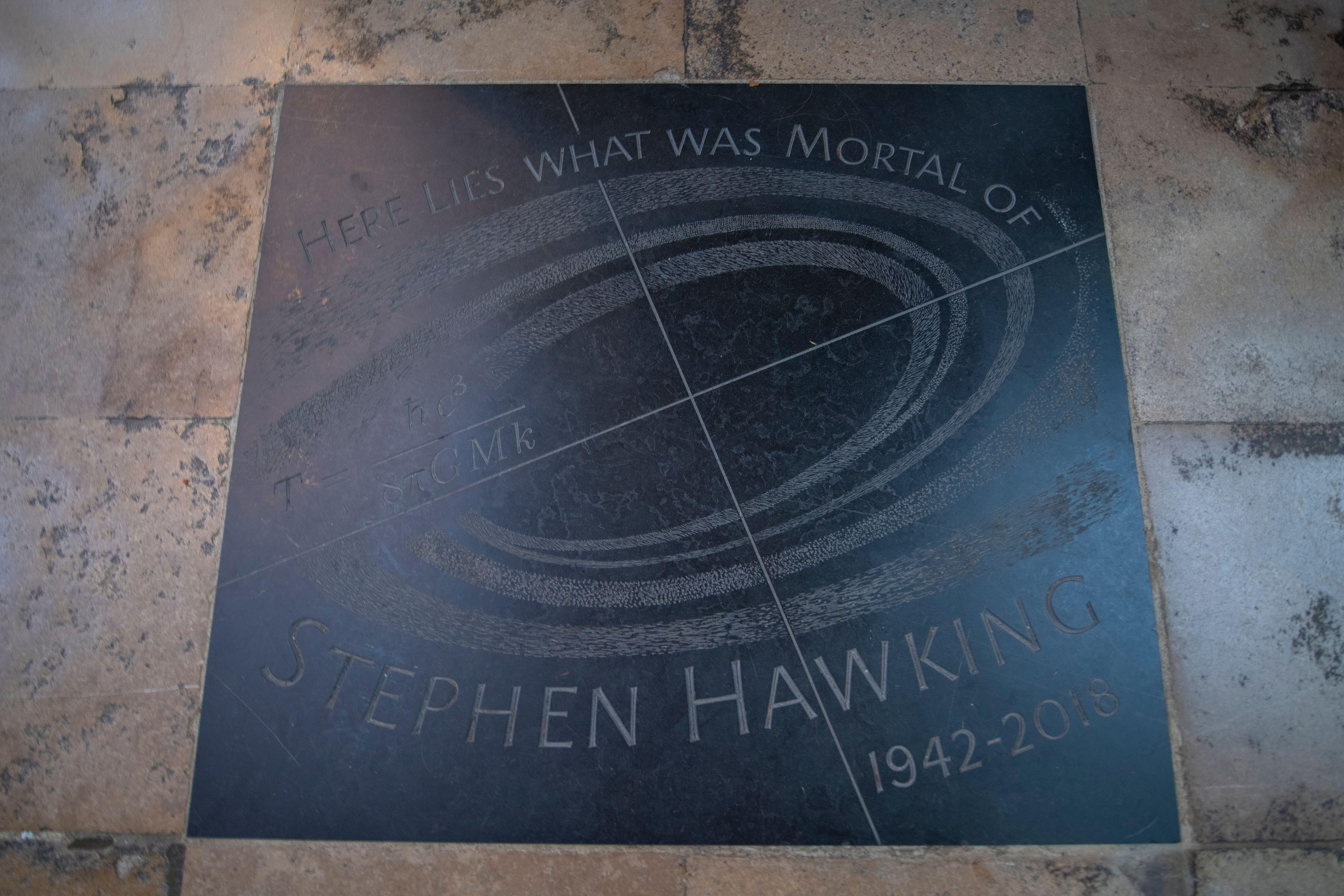 Stephen Hawking's memorial stone with an engraved swirl design, reading: "Here lies what was mortal of Stephen Hawking, 1942-2018."