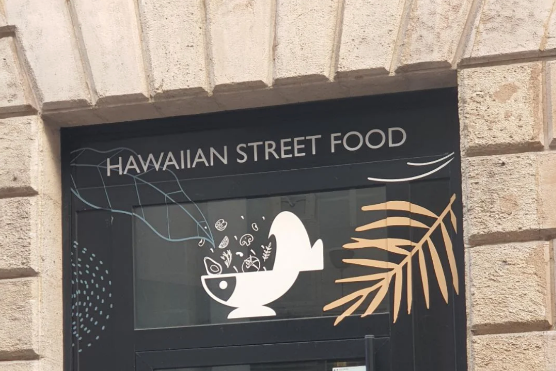 Sign above a doorway reads "Hawaiian Street Food" with a design of a bowl, fish, and leaves; however, the bowl looks like a toilet bowl