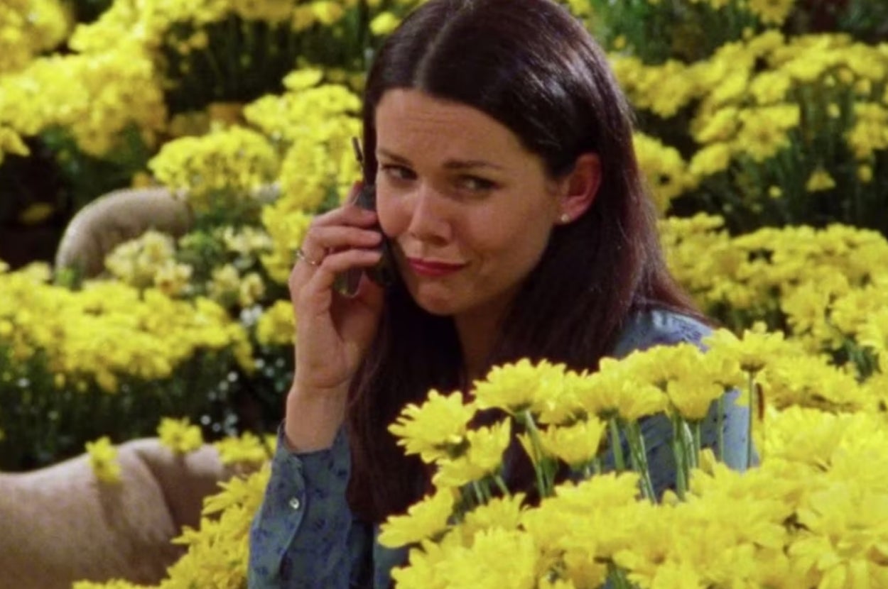 Person in a floral field talking on a smartphone, expressing disbelief