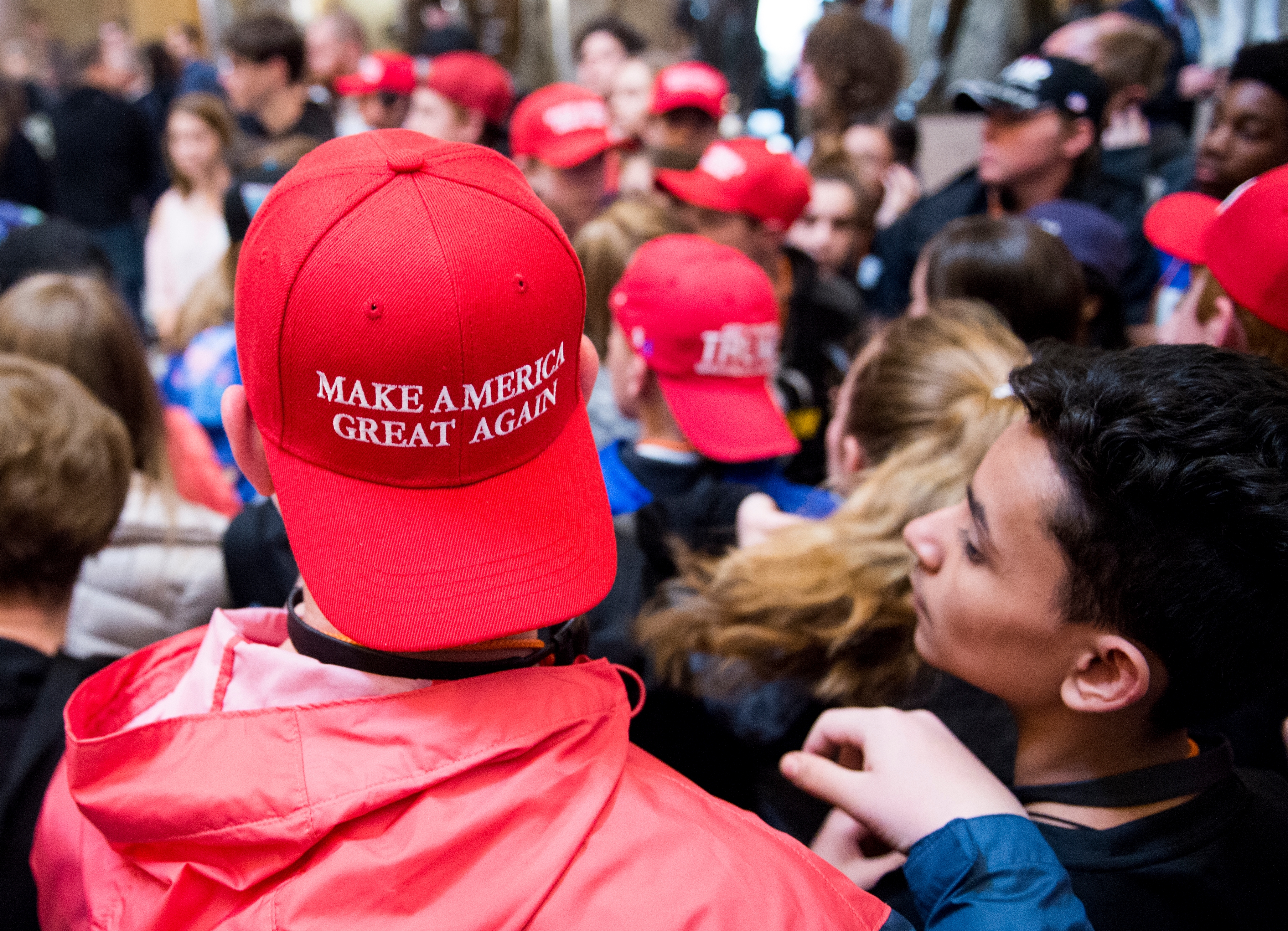 Person in a crowd wearing a &quot;Make America Great Again&quot; cap, surrounded by others in similar hats