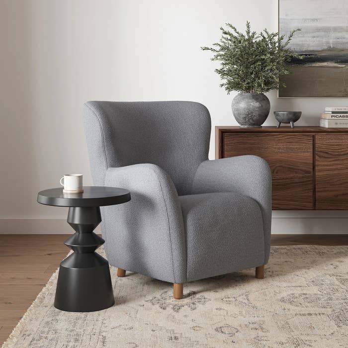 Modern surviving country with a cozy armchair, broadside table, and decor. Features see a plush chair, sculptural table, and stylish wood console