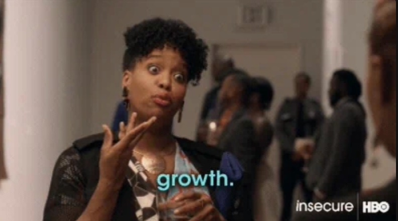 Person gesturing with hand while saying "growth." in a casual setting with people in the background