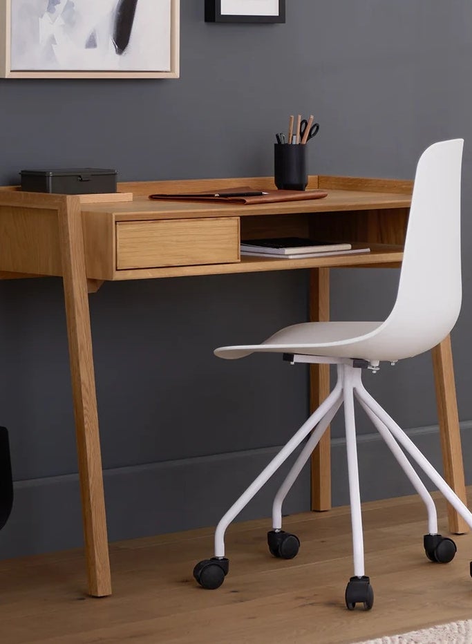 Minimalist wooden desk with a white swivel chair, featuring a few organized stationery items; ideal for a modern home office setup