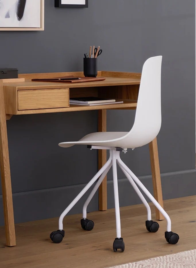 Minimalist wooden desk with a white swivel chair, featuring a few organized stationery items; ideal for a modern home office setup