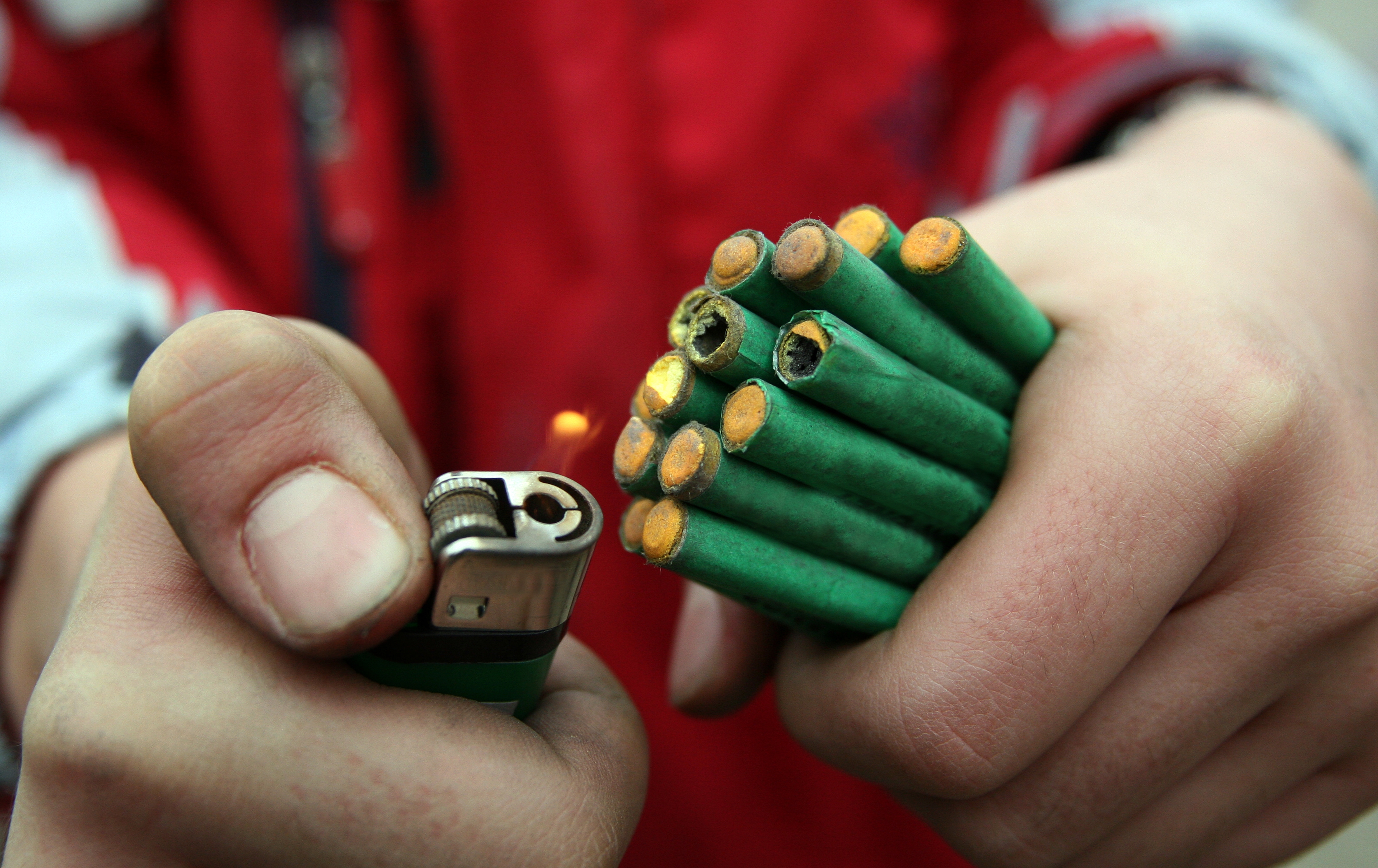 Hands holding and lighting a bundle of firecrackers with a lighter