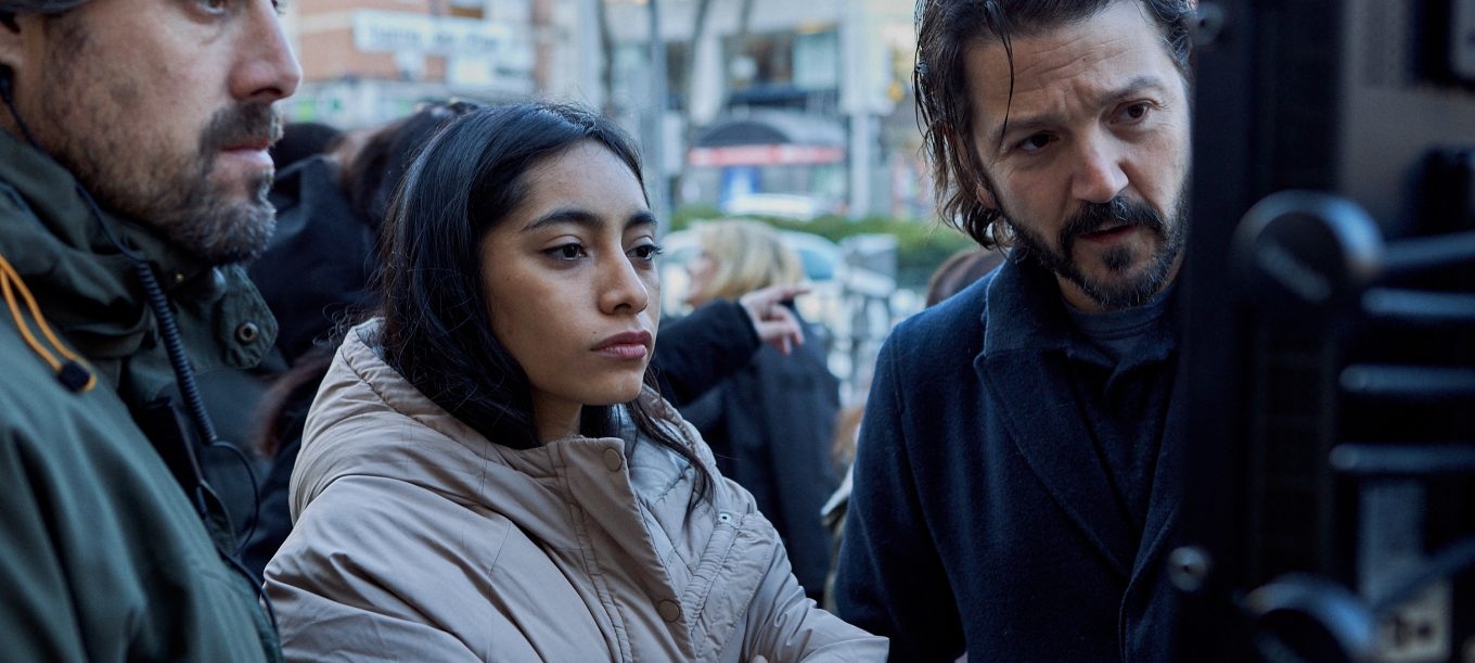 Un grupo de personas observa con atención una pantalla en un set de filmación al aire libre