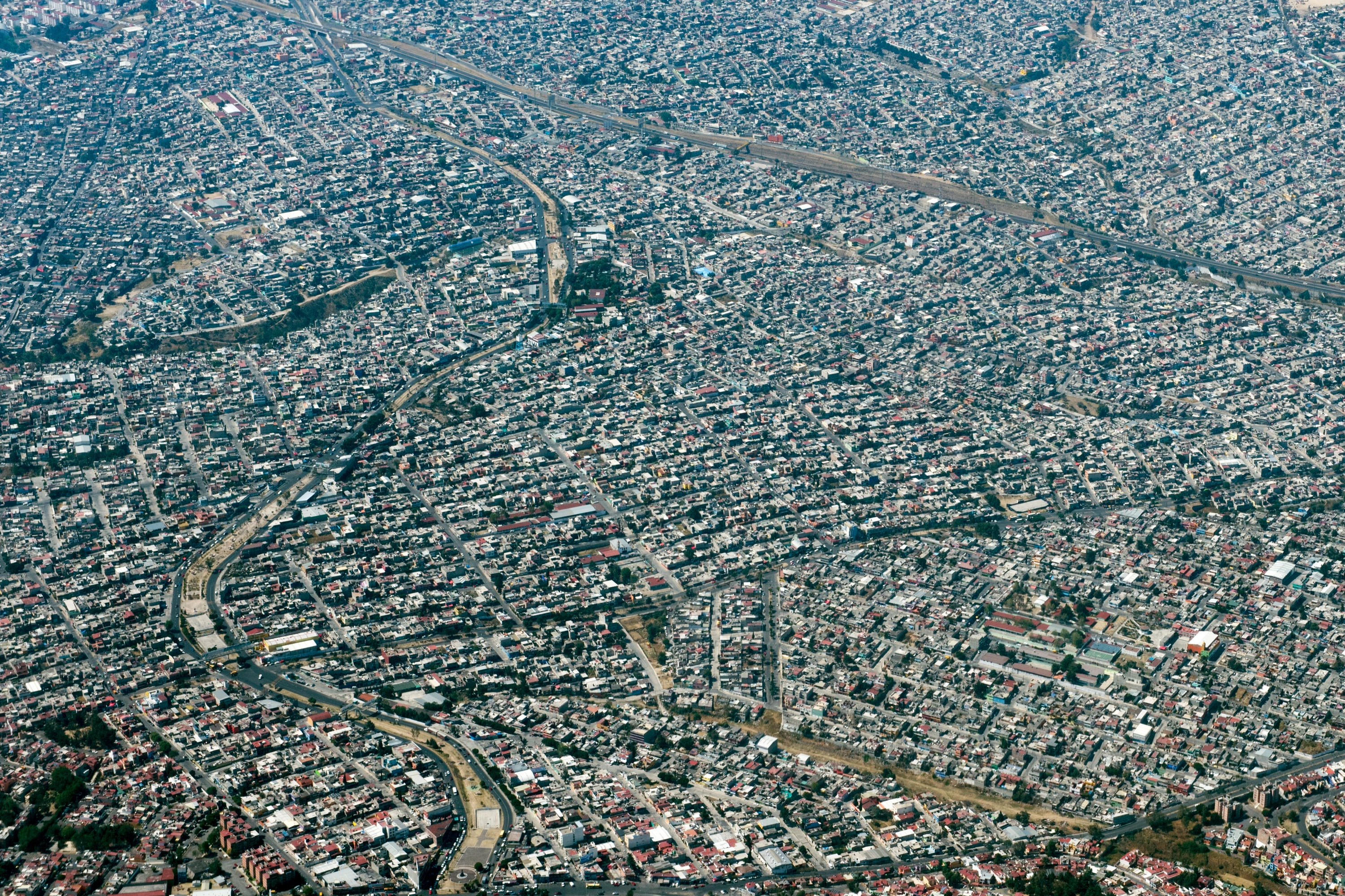 Aerial view of a densely packed urban cityscape with numerous tightly clustered buildings and winding roads