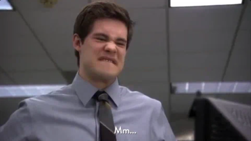 Person in an office, wearing a shirt and tie, making a facial expression with a slight grimace