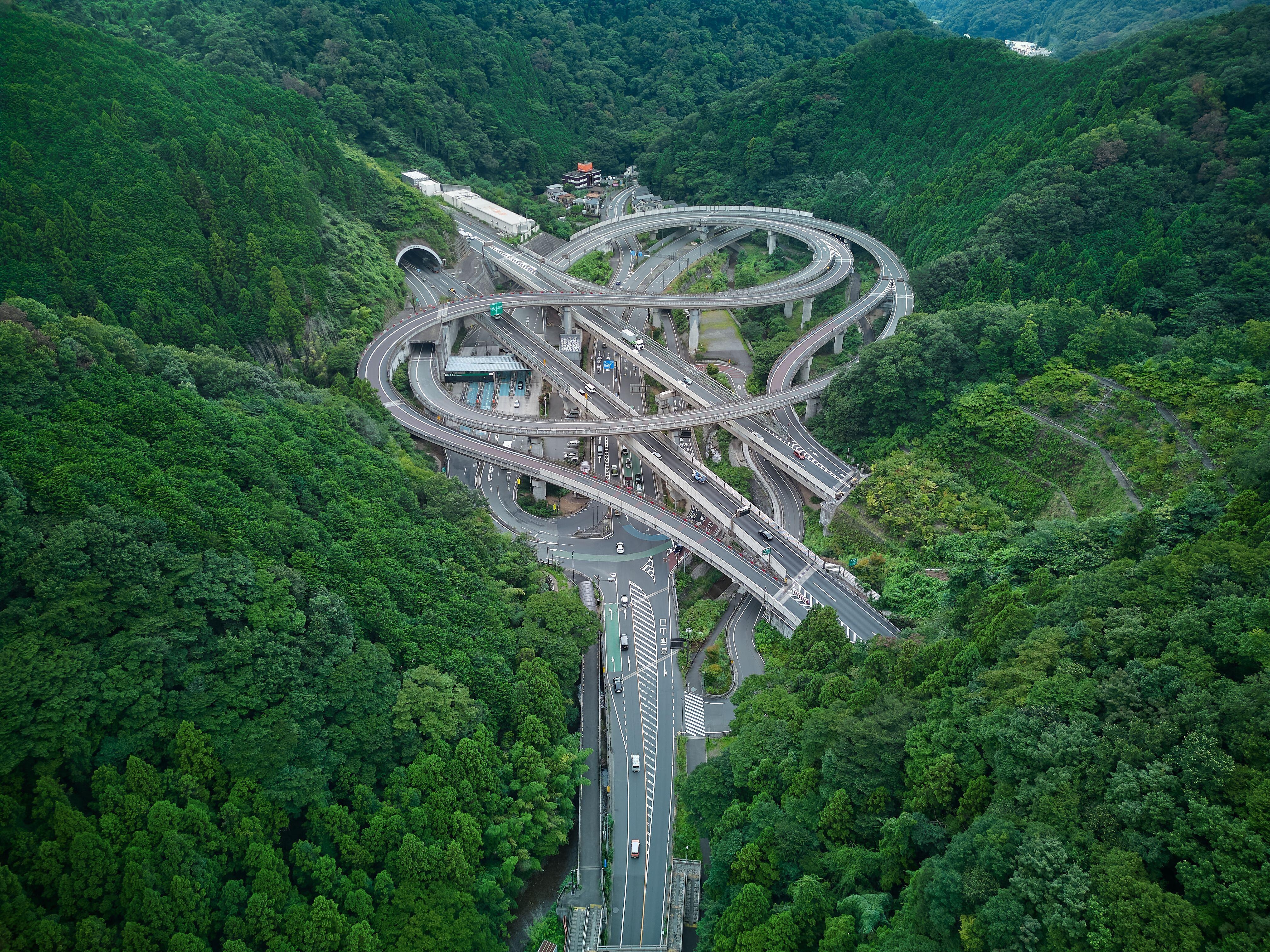 Aerial view of a complex highway interchange surrounded by lush green forest