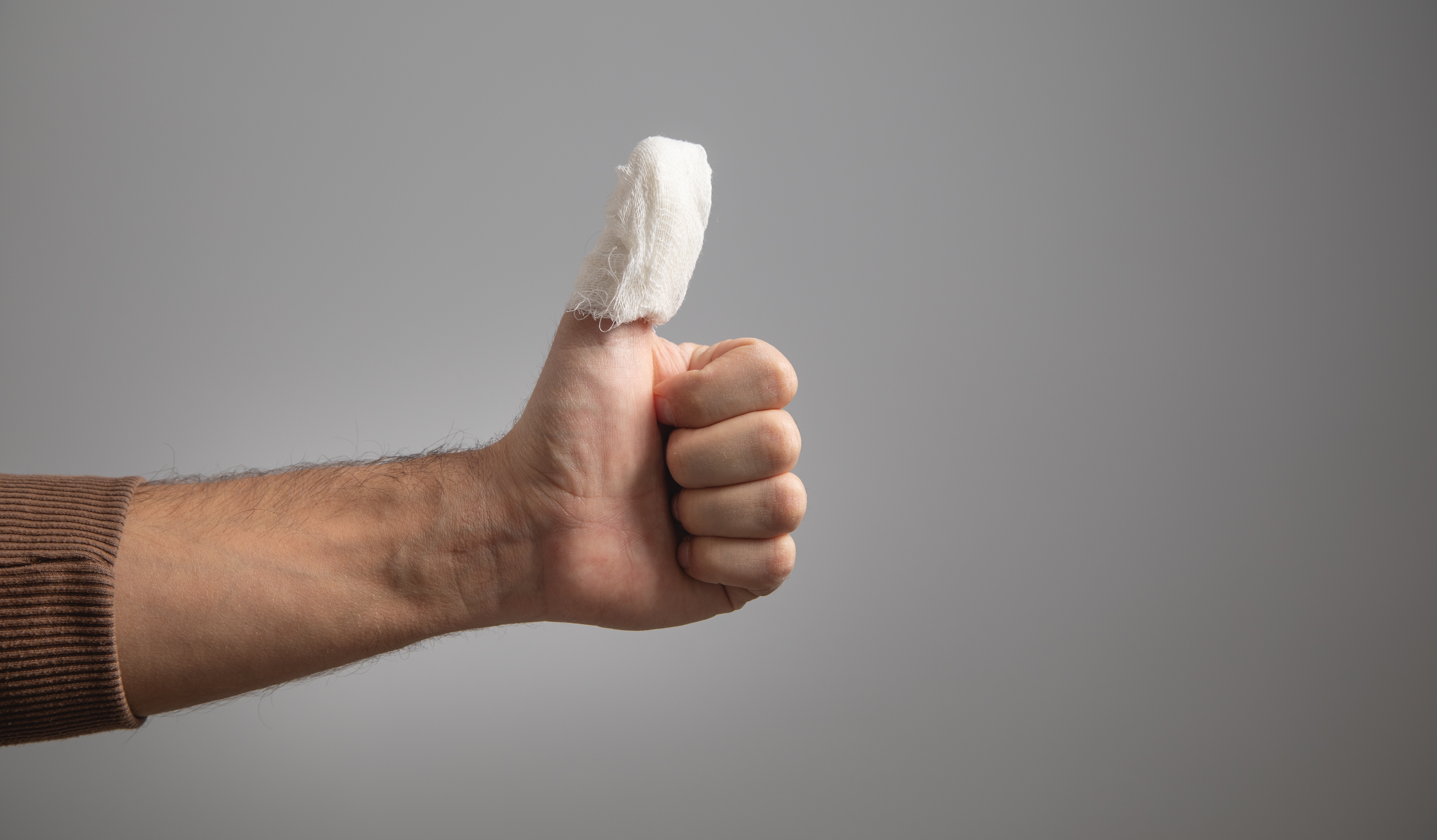 A person giving a thumbs up with a bandaged thumb, suggesting either an injury or protection for the thumb