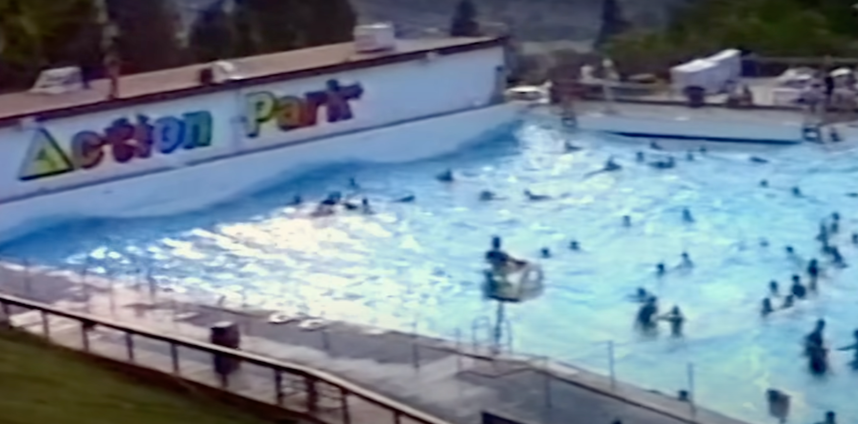 People swimming in a crowded wave pool at Action Park, with a lifeguard on duty