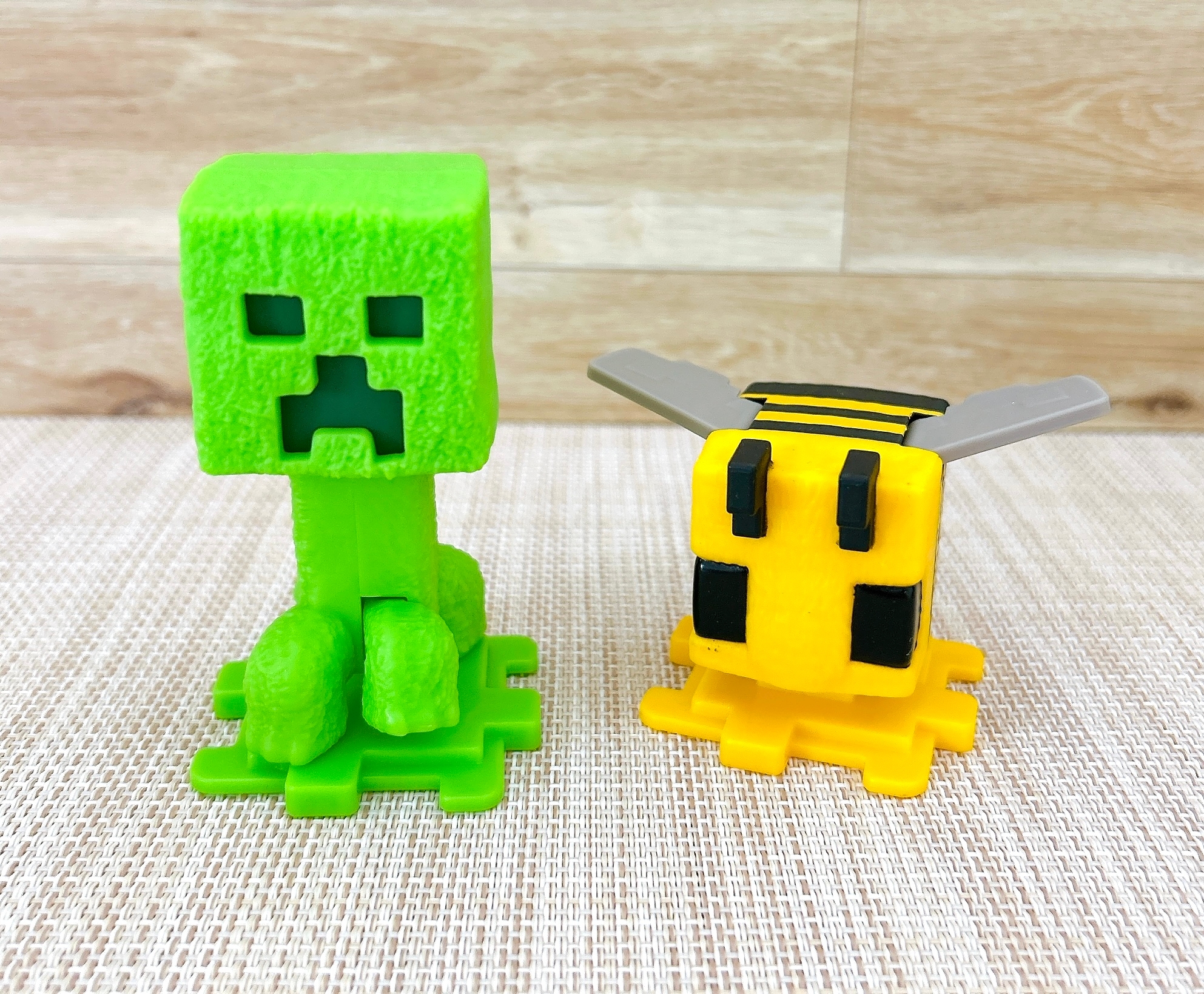Minecraftのクリーパーとハチのフィギュアがテーブルに並んでいる。