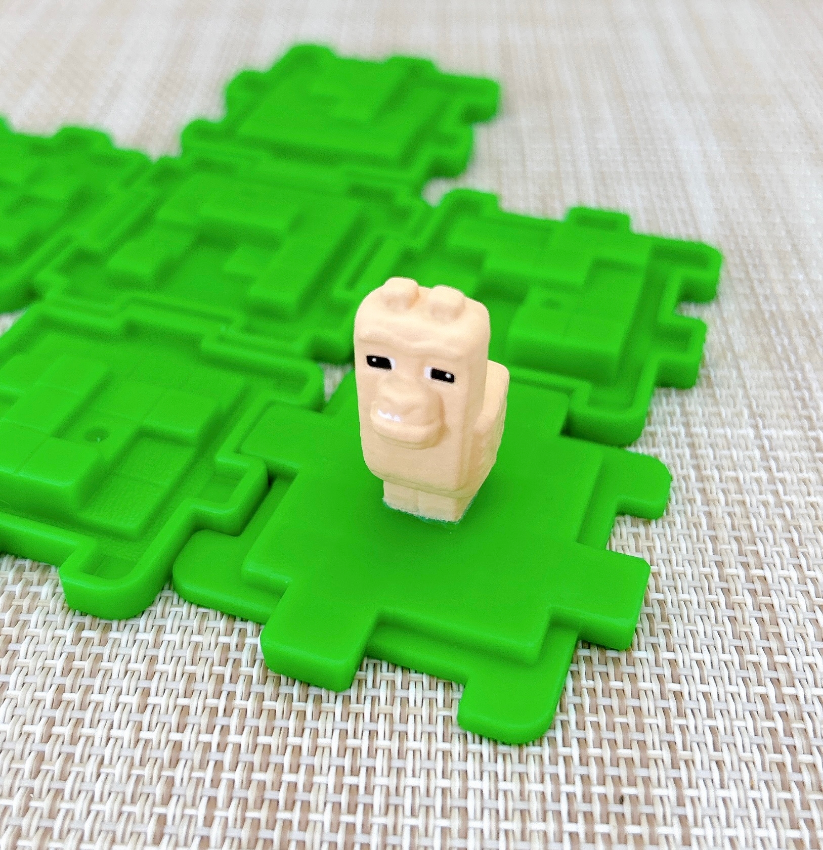 緑のパズルピースの上に小さなブロック製の動物フィギュアが置かれています。