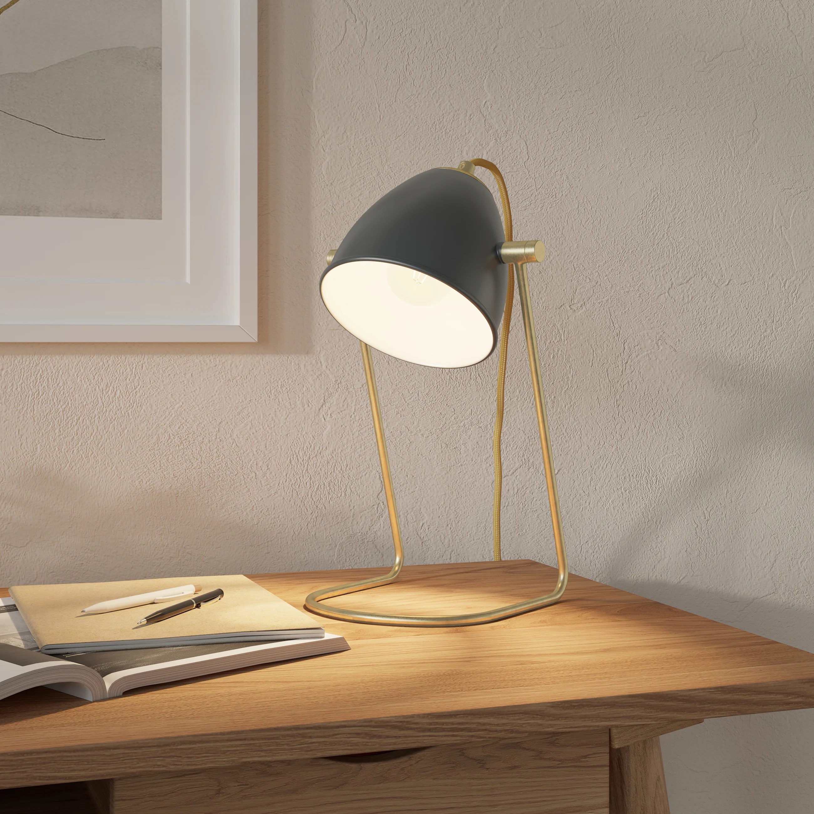 Modern desk lamp with a sleek, curved design on a wooden table next to an open book and pen
