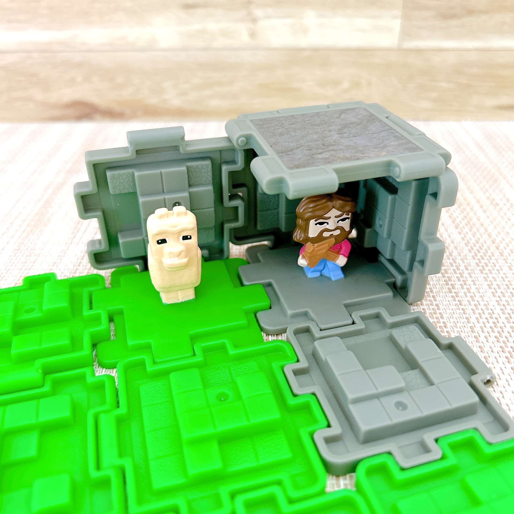 小さなフィギュアが、緑と灰色のブロックで作られたディオラマ内に配置されています。