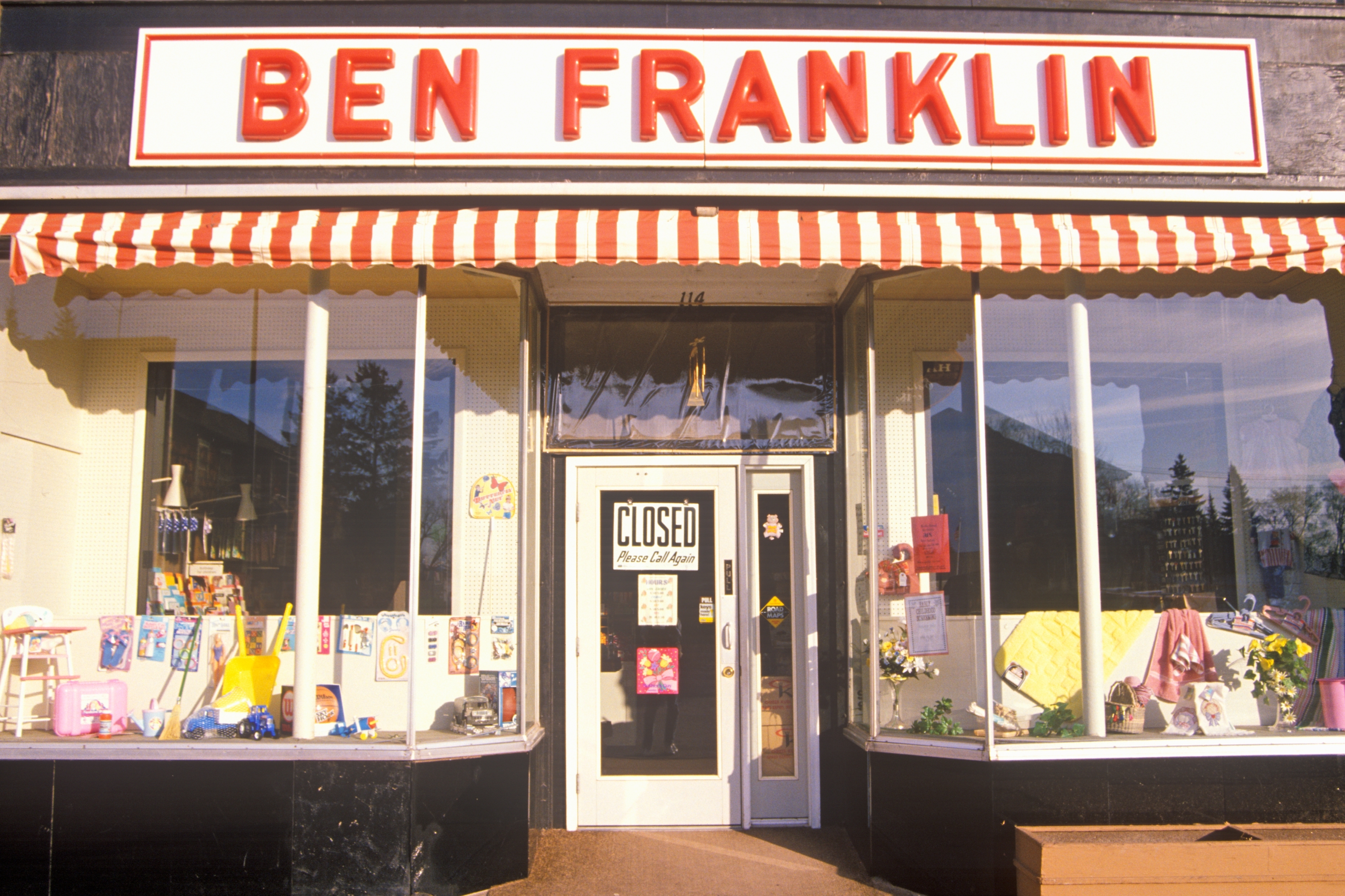 Storefront of Ben Franklin with closed sign on door. Display windows showcase various items, including crafts and decorations