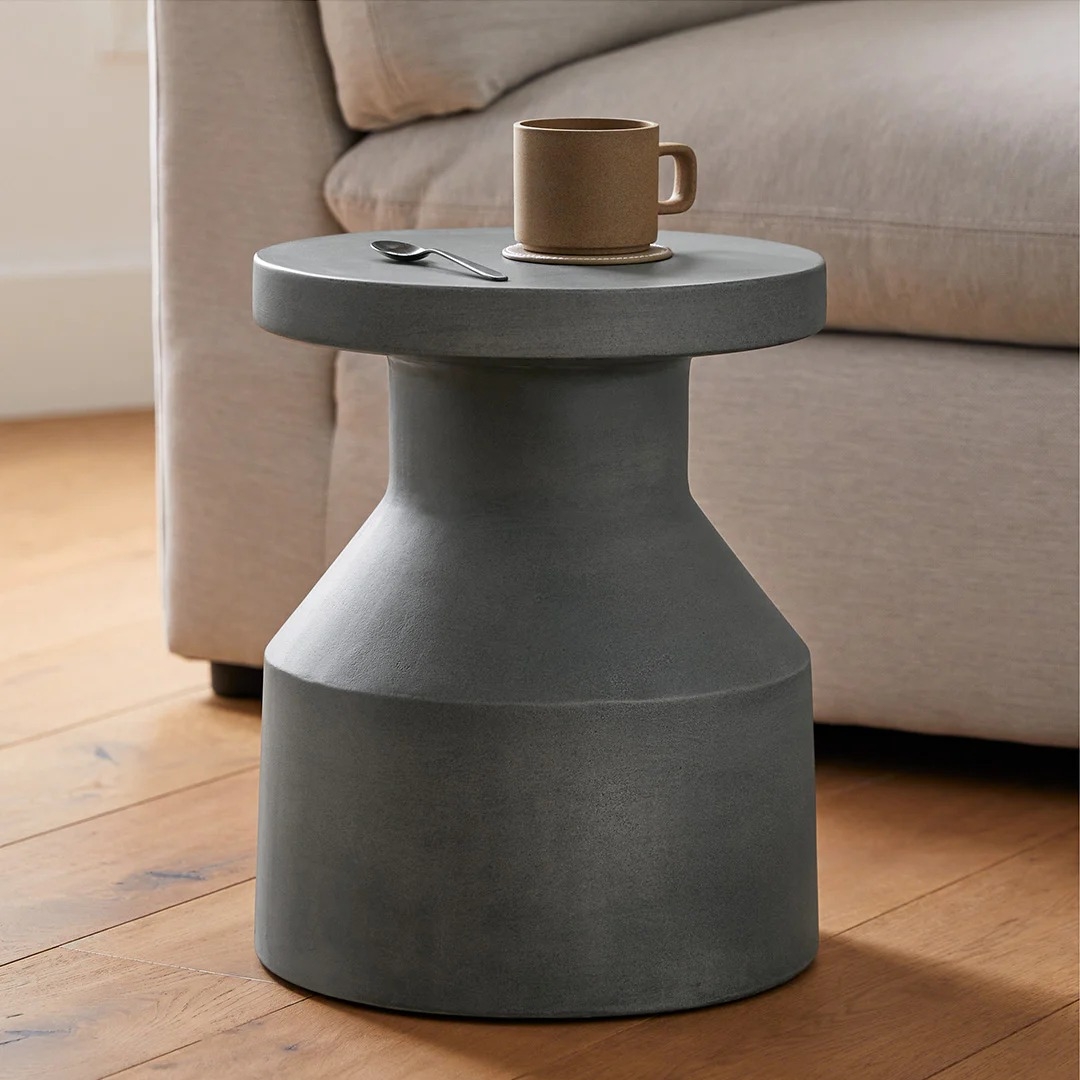 Modern gray side table near a beige sofa with a coffee mug and spoon on top. Suitable for stylish, functional living room decor