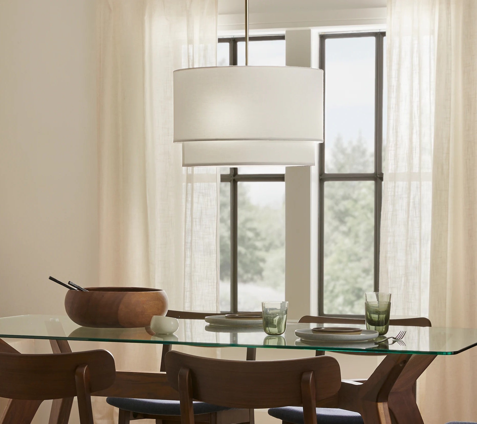 Dining room with a glass table, six wooden chairs with blue cushions, and a pendant lamp, set on a patterned rug