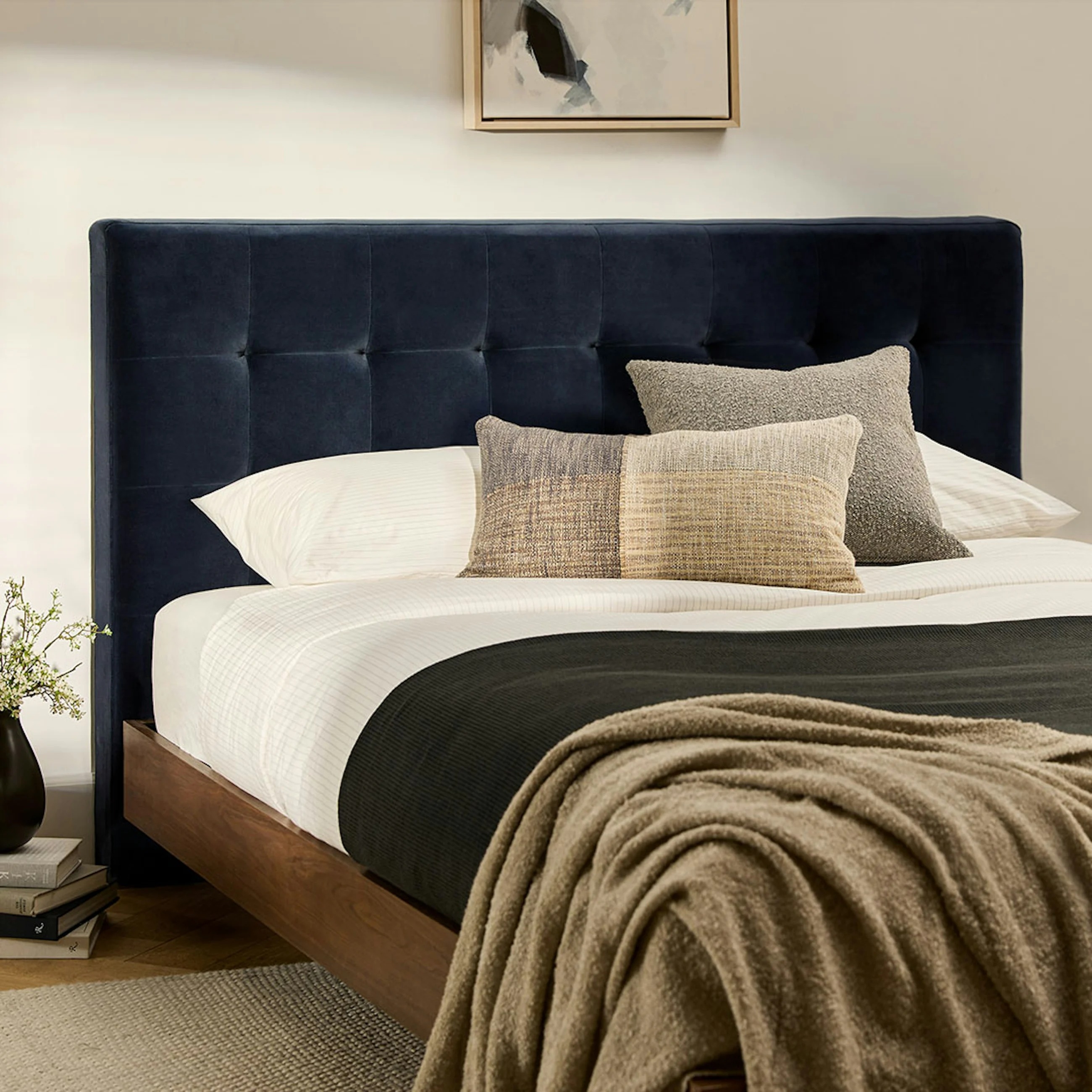 Bedroom with a modern bed, tufted headboard, layered pillows, and a cozy blanket, creating a stylish and inviting atmosphere